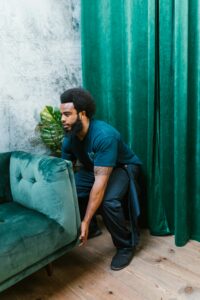 A man skillfully lifting a green sofa in a modern indoor living space.